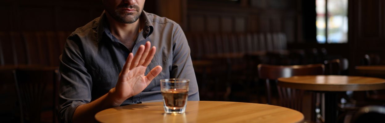 Мужчина отказывается от стакана коньяка